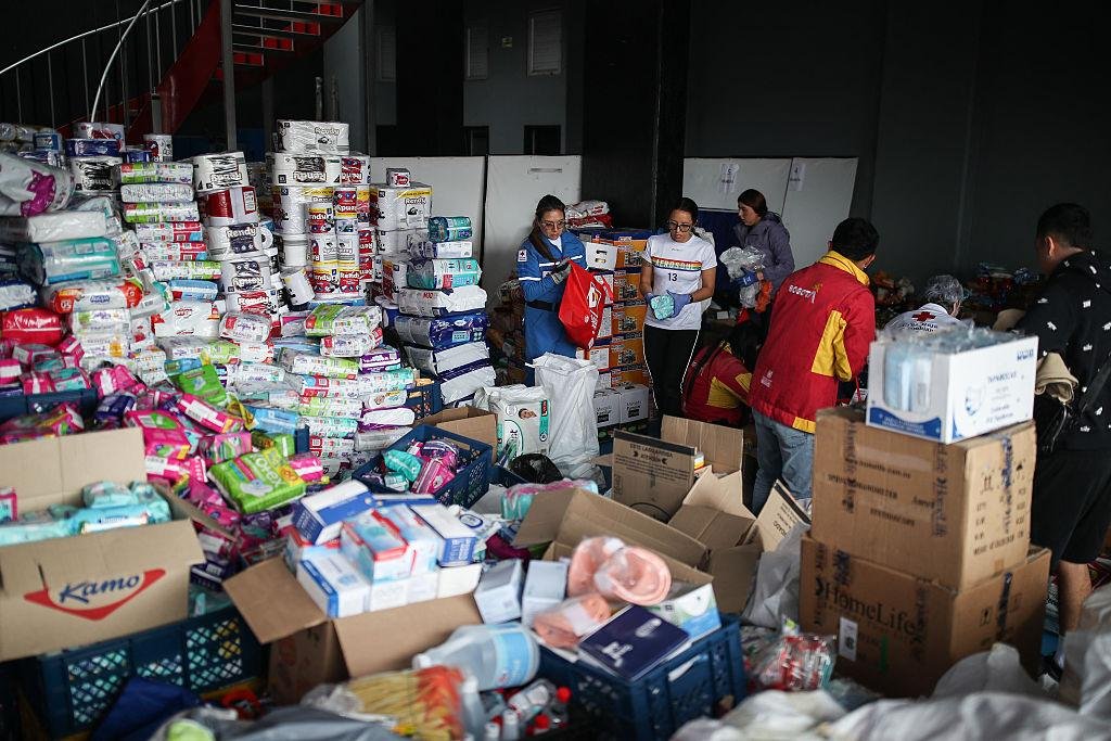 Centro de acopio con insumos humanitarios clasificados y voluntarios trabajando
