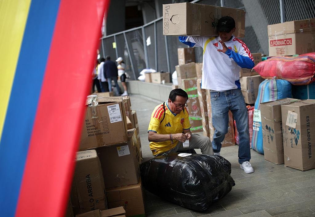 Personas movilizando cajas de ayuda humanitaria junto a los colores de Colombia