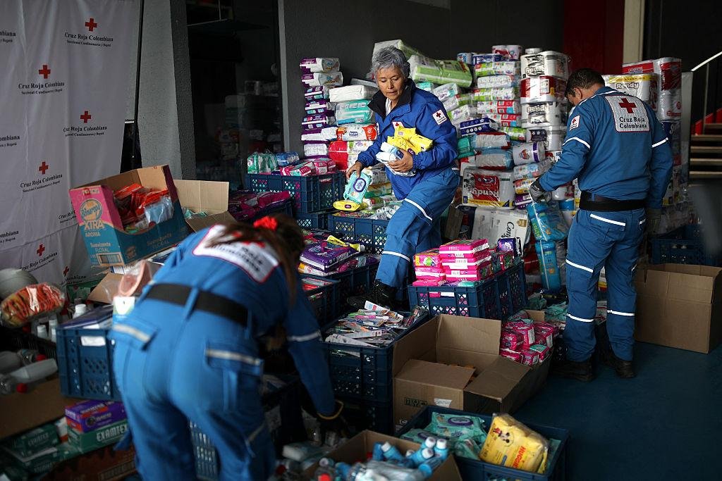 Voluntarios clasificando alimentos e insumos de aseo en un punto de acopio
